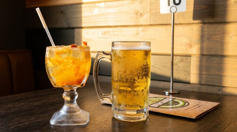 A refreshing cocktail with fruit and a frosty beer mug on a wooden table.