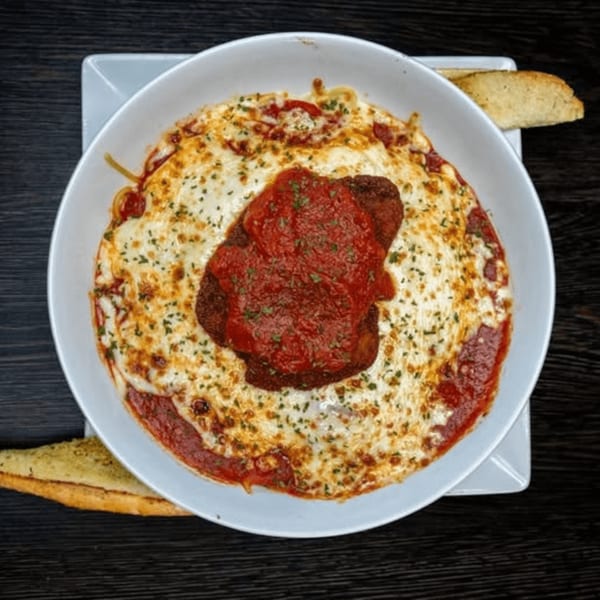 Chicken parmesan with melted cheese and marinara sauce, served with garlic bread.